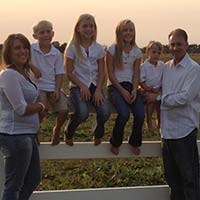 Photo of family sitting and leaning on a fence