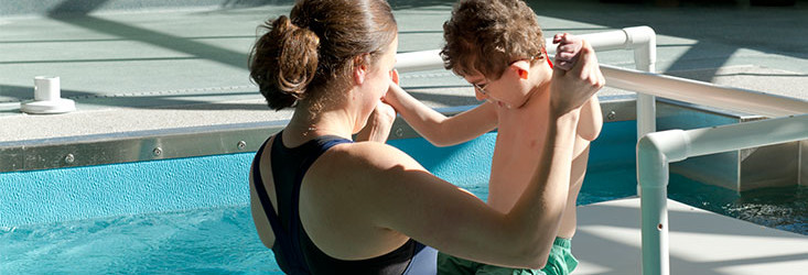 Adult doing water therapy with child