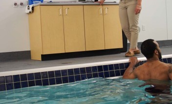 Person stretching in pool with trainer advising