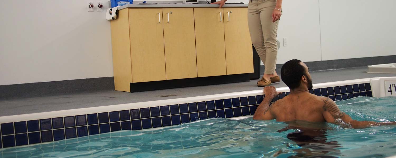 Person stretching in pool with trainer advising