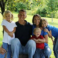 Family smiling and posing by trees for photo