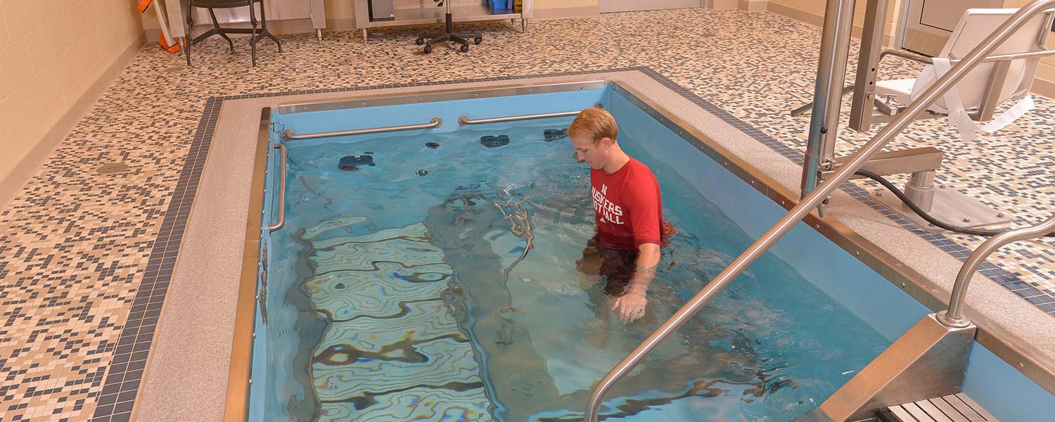 Person training in pool wearing Huskers shirt