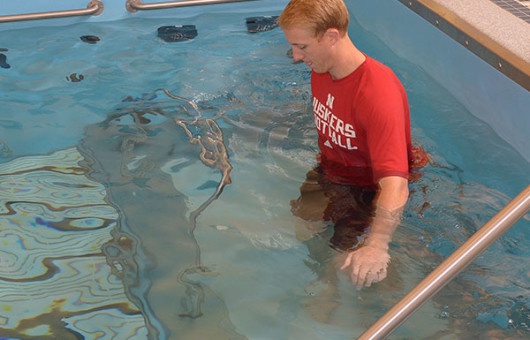 Person in Huskers shirt training in HydroWorx pool