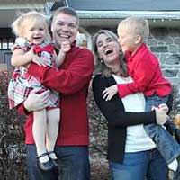 Family holding children in front of a house