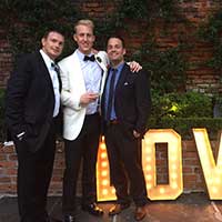 Three people in suits and bow ties posing for photo
