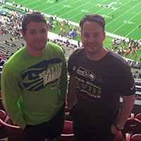 Two Seahawks fans standing at a football game