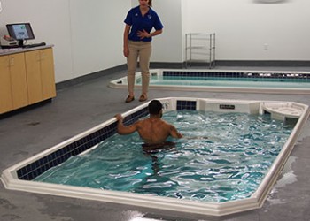 Person stretching in pool with trainer advising