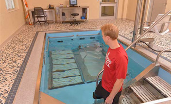 Person in Huskers shirt walking into HydroWorx pool