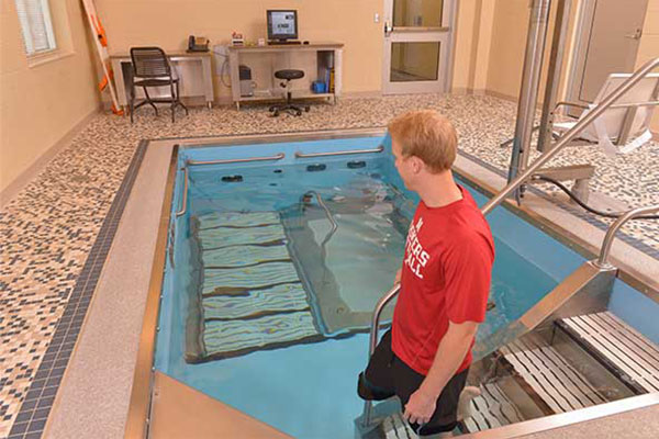 Person in Huskers shirt walking into HydroWorx pool