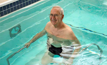 Person standing in pool holding metal bars