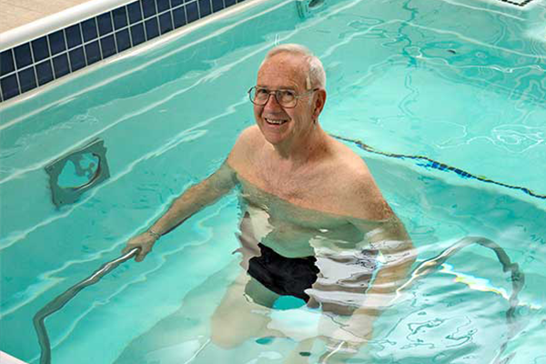 Person standing in pool holding metal bars