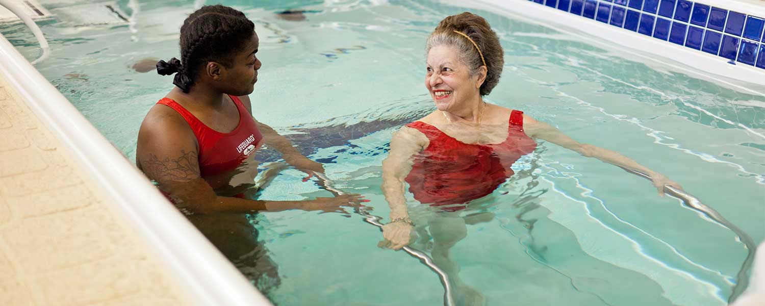 Lifeguard helping pool trainee