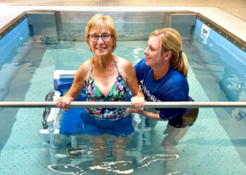 older woman using aquatic pool with female trainer