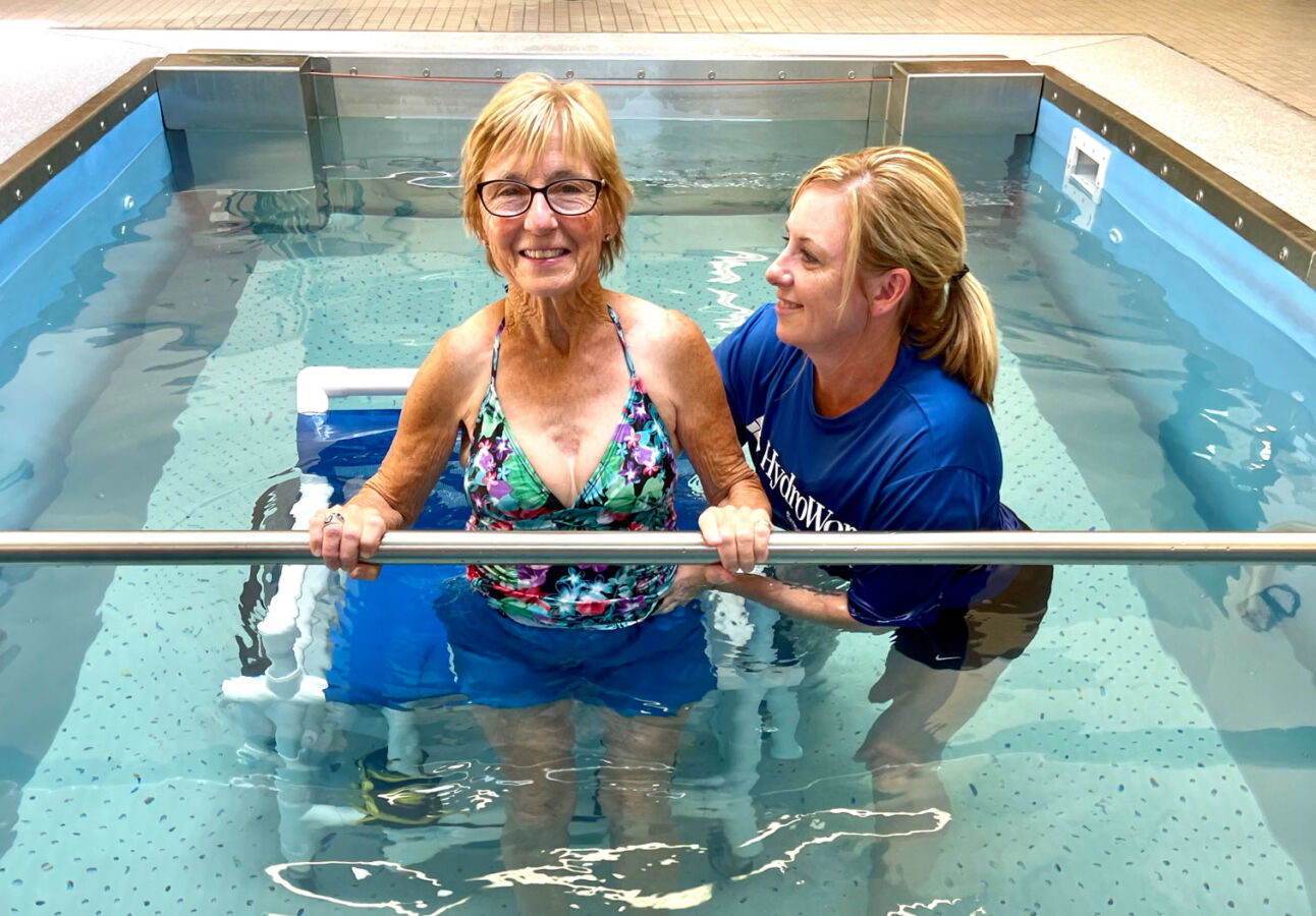 older woman using aquatic pool with female trainer