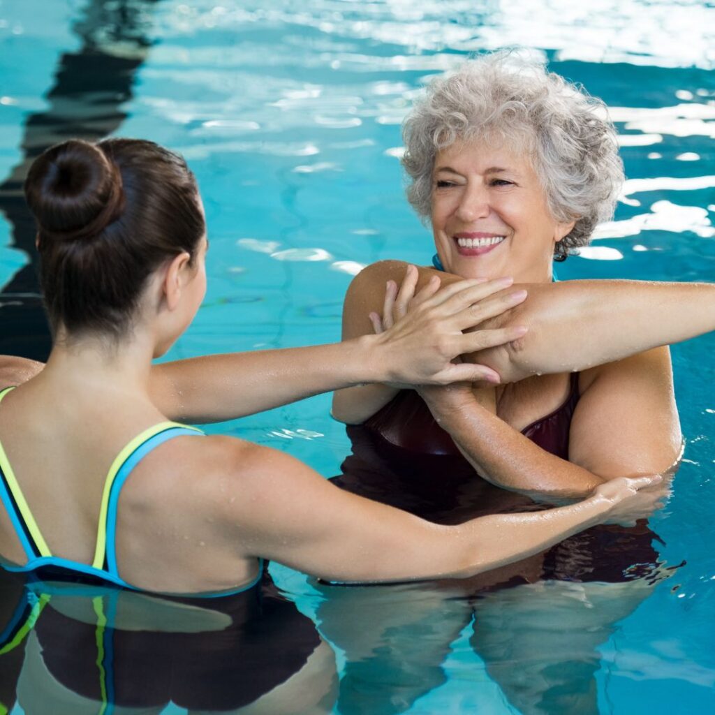 woman stretching in pool with trainer